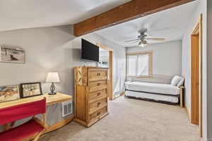 Snow Flower 72s bedroom with a twin bed with twin trundle, and blonde wood dresser, flat screen TV, and desk table.