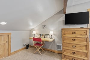 Snow Flower 72sloft bedroom with a blonde wood dresser, flat screen TV, and desk with red chair, pictures and lamps on it.