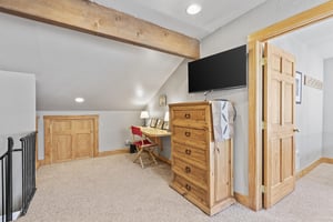 Snow Flower 72sloft bedroom with a blonde wood dresser, flat screen TV, and desk with red chair, pictures and lamps on it.