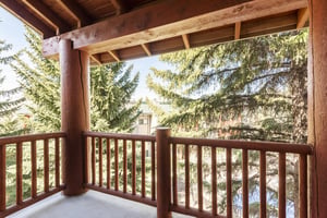 Private covered patio with large wood beams and railings.