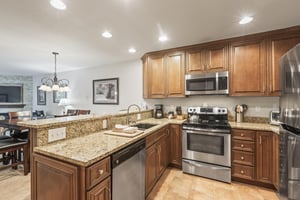 Snow Flower 135s kitchen with medium colored wood cabinets, granite counters, and stainless steel appliances.