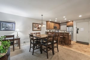 Snow Flower 135s dining area with a wood table, 6 dining chairs, and chandelier and open concept kitchen.