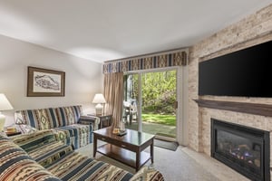 Snow Flower 135s living room with southwestern upholstered couch and sliding glass doors with green grass and trees beyond.