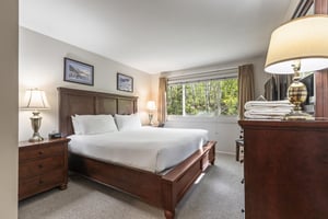 Snow Flower 135s bedroom with king bed, solid wood frame, large window with forest views, and wooden dresser.