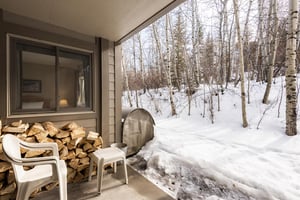 Relax on the private patio on white chairs next to freshly fallen snow and the aspen grove.