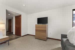 The fourth bedroom has a wooden dresser and TV.