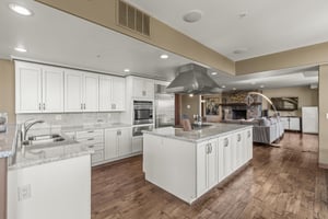 The spacious kitchen has many white cabinets, a wrap around counter and breakfast bar, and freestanding island.