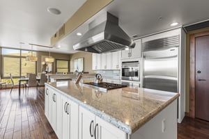 The spacious kitchen has a stainless steel refrigerator, microwave, and hood vent.