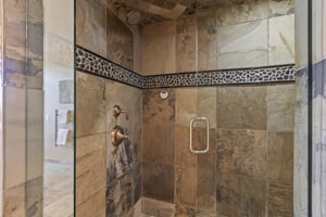 The main bedrooms en suite bathroom has a walk in shower with stone and tile surround.