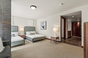 The hotel style bedroom offers two queen beds and white art above the beds.