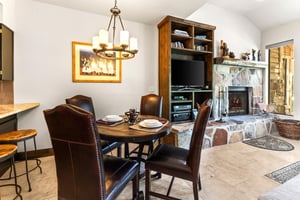 Queen Esther 2425s dining area with seating for 4 on leather chairs and a round table and art on the wall behind.