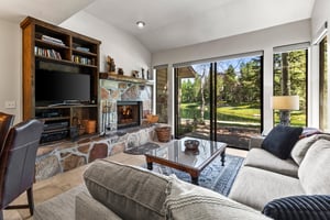 The living room has a builtin wood fireplace with stone surround and builtin cabinet with flatscreen TV.