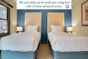 Lowell 304s second bedroom with two twin beds that have a large upholstered headboard and blue accent wall.