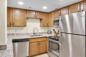 Park Station 214s kitchen offers stainless steel appliances, wood cabinets, and grey and white counter tops.