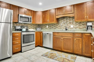 Park Station 113s kitchen has stainless steel appliances, wood cabinets, tile floors and interesting tile backsplash.