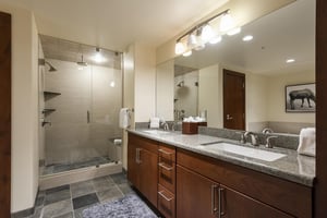 Main bathroom with double vanity, tile floors, and glass paneled shower