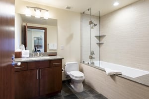 Ensuite full bathroom with vanity lights and step in showertub combo