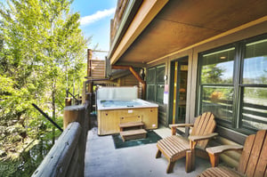 Spacious deck with private hot tub and wooden Adirondack lounge chairs