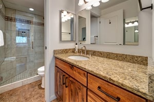 The main suite bathroom has a walk in shower and single vanity sink with granite countertop.