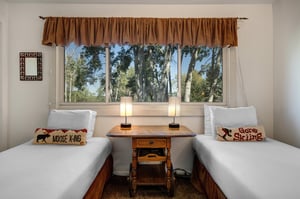 The second bedroom offers two twin beds with ski pillows and crisp white bedding.