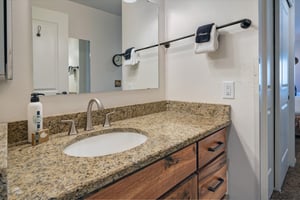 The second bedrooms shared bathroom has a  single vanity sink with granite countertop.