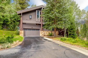 The Aspen Hollow 6 exterior is surrounded by green grass, trees, and other flowering plants.