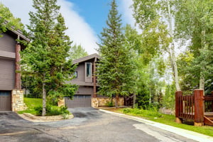 The Aspen Hollow 6 exterior is surrounded by green grass, trees, and other flowering plants.
