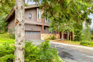 The Aspen Hollow 6 exterior is surrounded by green grass, trees, and other flowering plants.