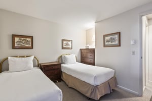 Snow Flower 135s second bedroom with two twin beds with white linens and pillows, and wooden dresser.