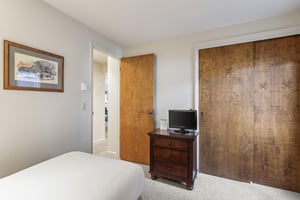 Snow Flower 135s second bedroom with twin beds with white linens and a small wooden cabinet with TV.