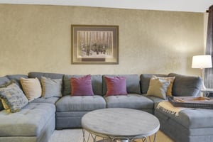 Park Station 122s living room has a grey upholstered sofa, throw pillows, modern round coffee table, and picture on the wall.