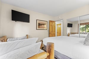 The second bedroom with a queen bed, twin bed and wall mounted TV.