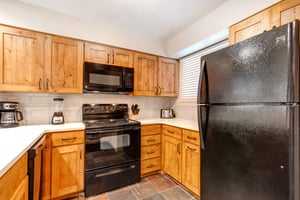 The well equipped kitchen with black appliances and wood cabinets.