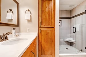 The shared bathroom offers a walkin shower with tile surround and one sink vanity.