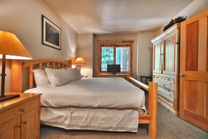 First bedroom with a king size bed and large wooden armoire.