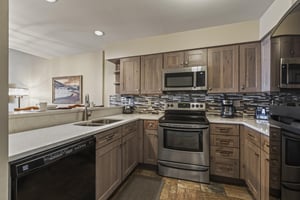 Snow Flower 127 has a wellequipped kitchen with wood cabinets and black and stainless steel appliances.
