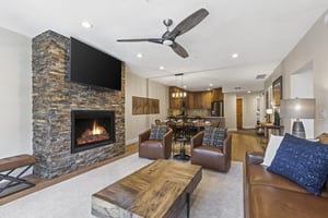 Town Pointe B204s living room with a gas burning fireplace and flat screen TV.