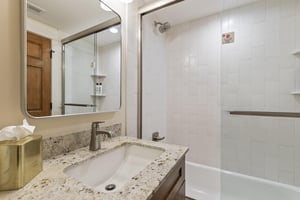 The bathroom with a bathtub and shower combination and single sink vanity