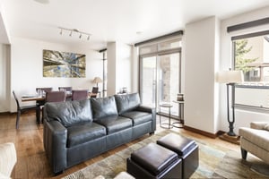 Natural light floods the living area, leather couch and foot rests