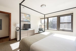Main bedroom with wooden drawer, window lounge chair, and TV