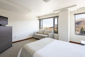 Queen bed and queen sofa sleeper below a large picture window