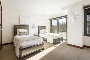 Third guest bedroom with two twin beds, leather style headboards, and bright window wall