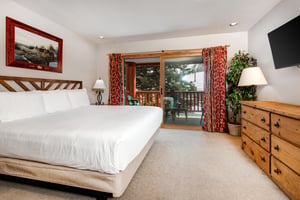 Snow Flower 20s main suite has a kingsize bed and wooden furnishings and sliding glass doors to a private patio.