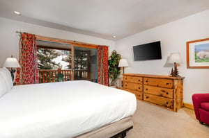 Snow Flower 20s main suite has a kingsize bed and wooden furnishings and sliding glass doors to a private patio.