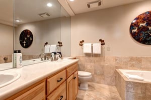 The en suite bathroom has a spacious two sink vanity and deep soaker bathtub.