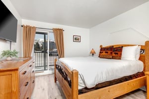 The main suite has a kingsize bed, wood furnishing and sliding glass doors leading to a patio.