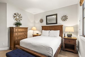 The third bedroom has a queen size bed and wood furniture.