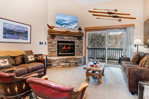 The living room has two leather couches and two unique accent chairs.