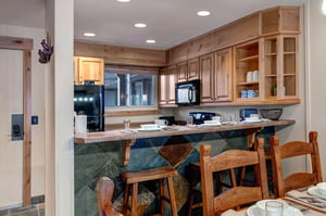 The open concept kitchen has a breakfast bar with seating for 3 and white place settings.