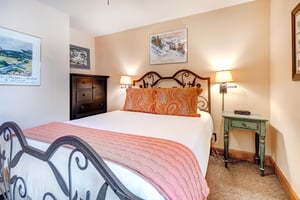 The second bedroom has a queensize bed with intricate metal frame.